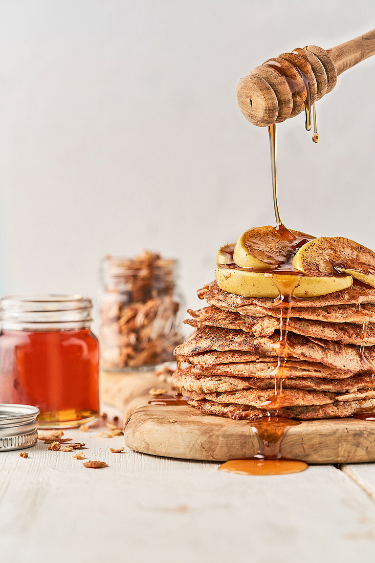 Pouring honey from dipper on crispbread and apple slices