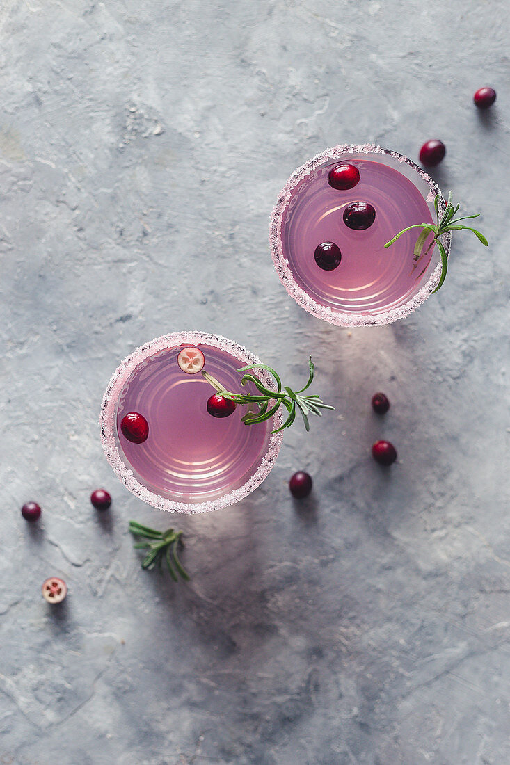 Two glasses of a cranberry and rosemary drink