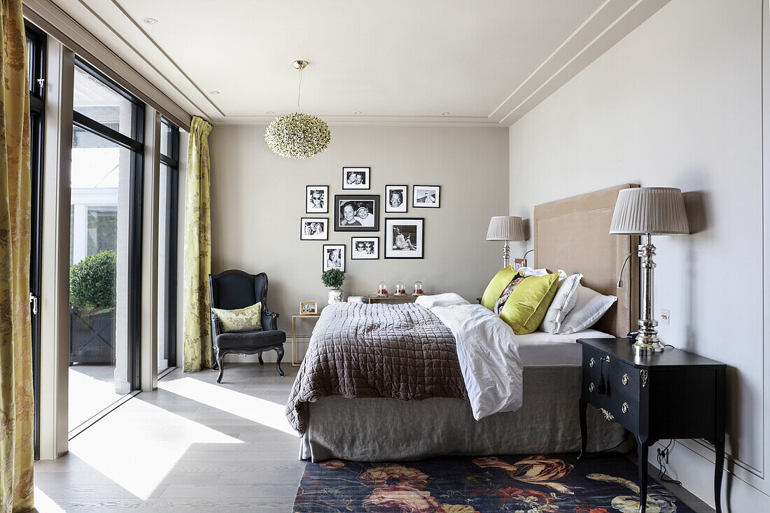 Double bed with high headboard and black and white photograph in bedroom with balcony