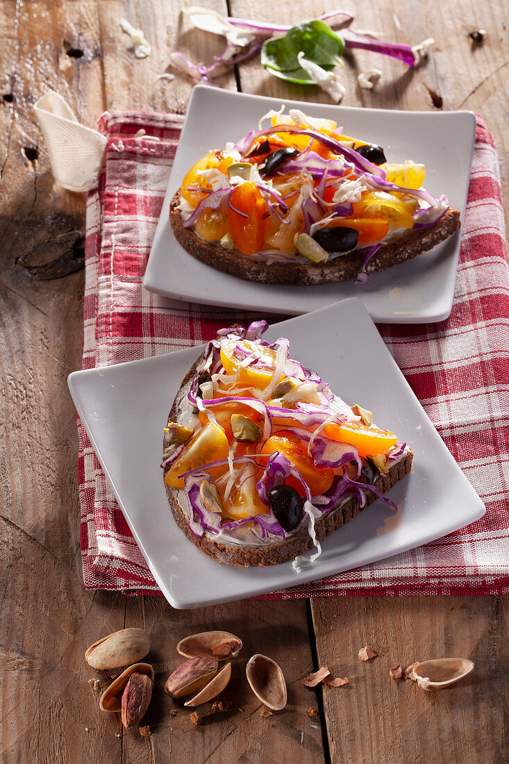 Brot mit veganer Mayo, gelben Kirschtomaten, Oliven und Pistazien