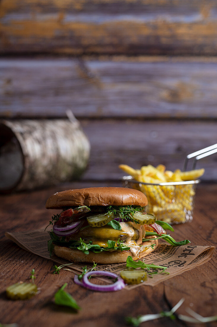 Cheeseburger mit Essiggurken und Zwiebeln dazu Pommes frites