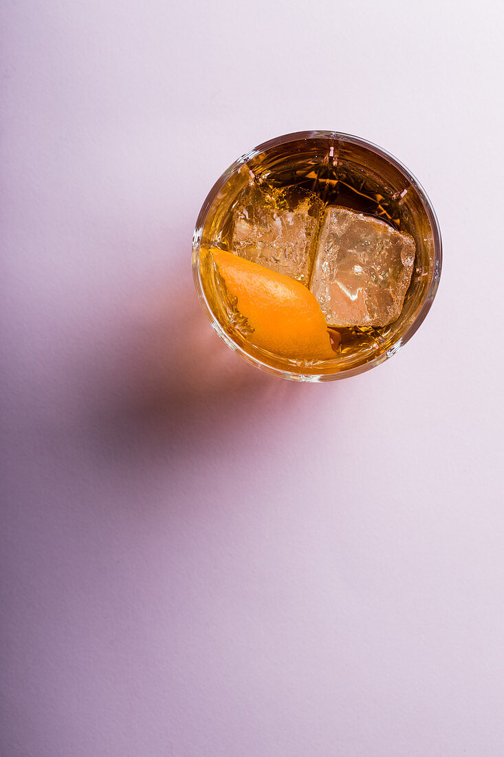Old fashioned cocktail with orange slice and ice cubes