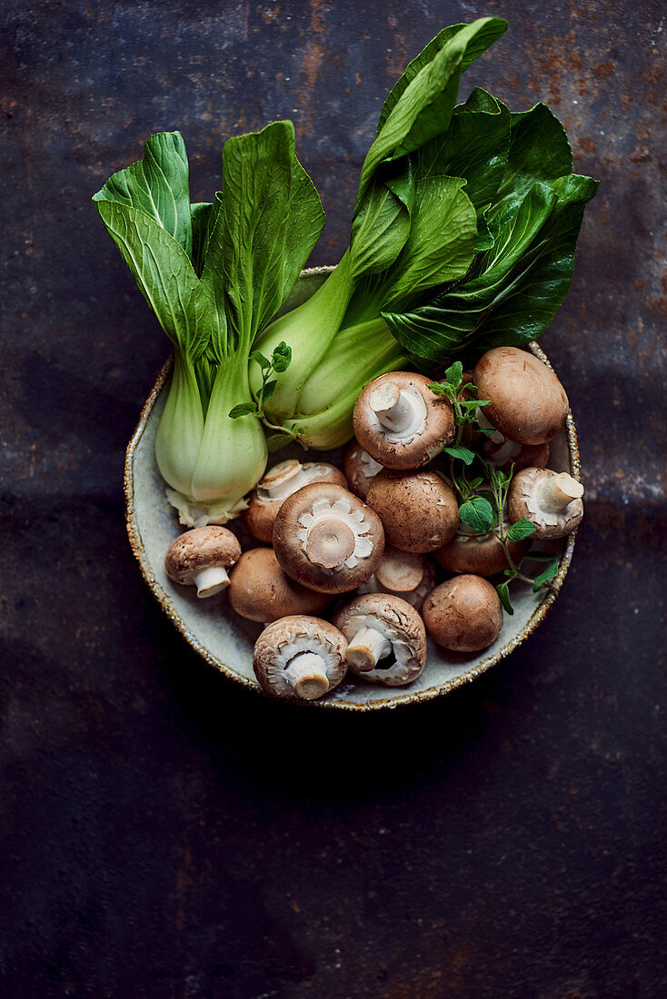 Pak Choi und braune Champignons in Keramikschale