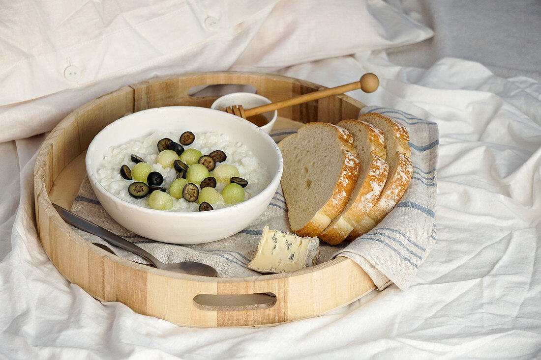 Porridge mit Früchten auf Frühstückstablett im Bett