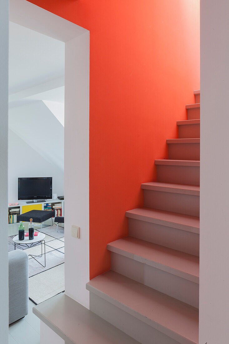 View from staircase with salmon-pink wall into living room