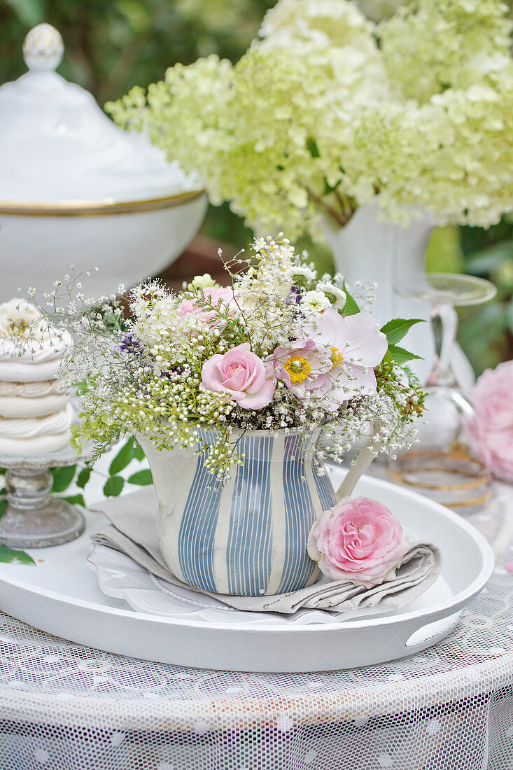 Pastel bouquet with rose, autumn anemone, and gypsophila (baby's breath) in a cream pitcher