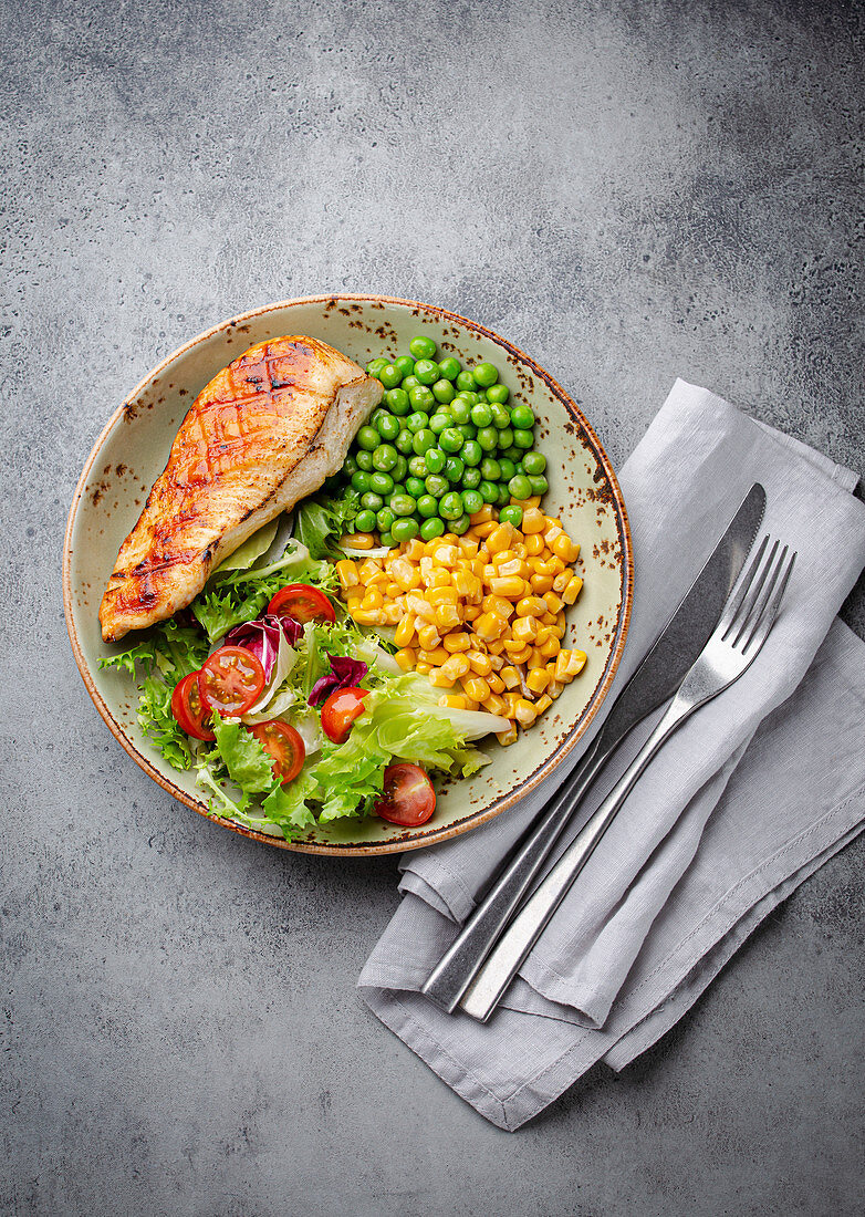 Gebackene Hühnerbrust mit frischem Salat, grünen Erbsen und Mais