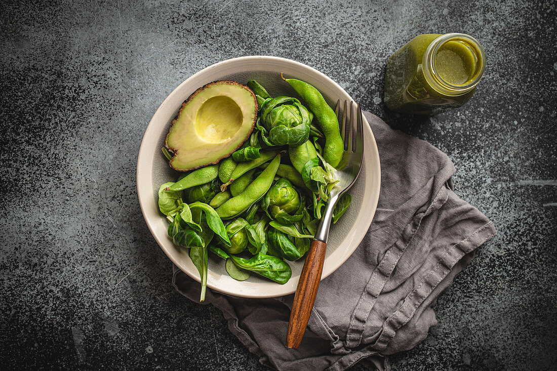 Green healthy salad with spinach, brussels sprouts, avocado in bowl and green detox smoothie