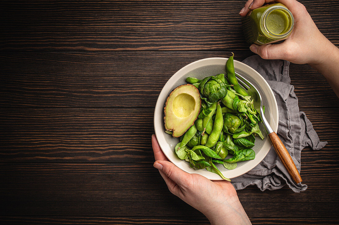 Green healthy salad with spinach, brussels sprouts, avocado in bowl and green detox smoothie