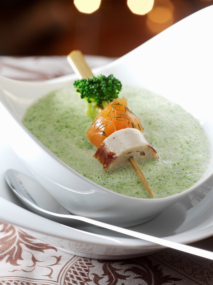 Cream of broccoli soup with salmon and sausage on a skewer