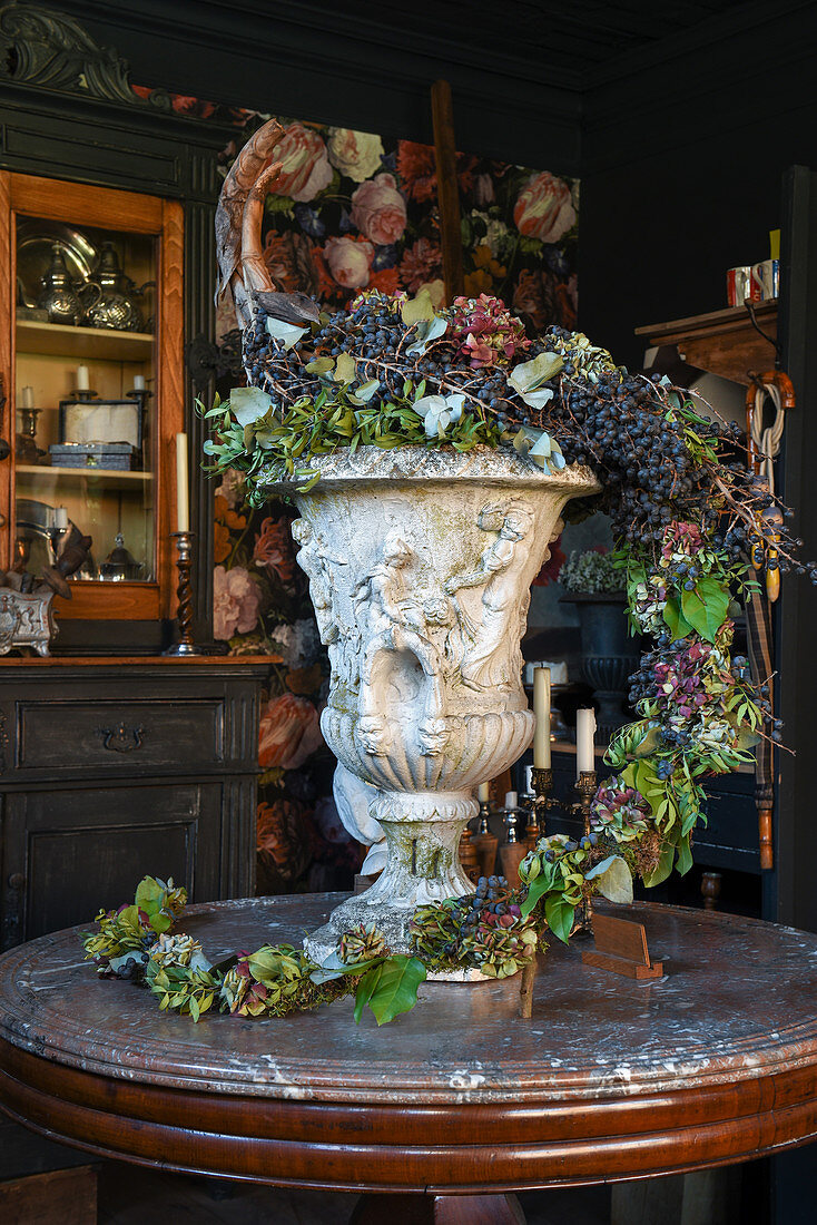 Ambitious, autumnal flower arrangement with grapes in urn