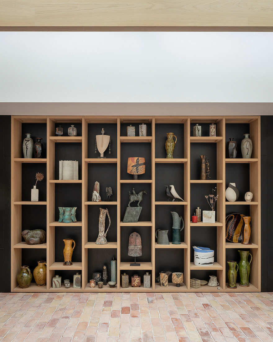Vases, jugs and sculptures on modern shelves against dark wall