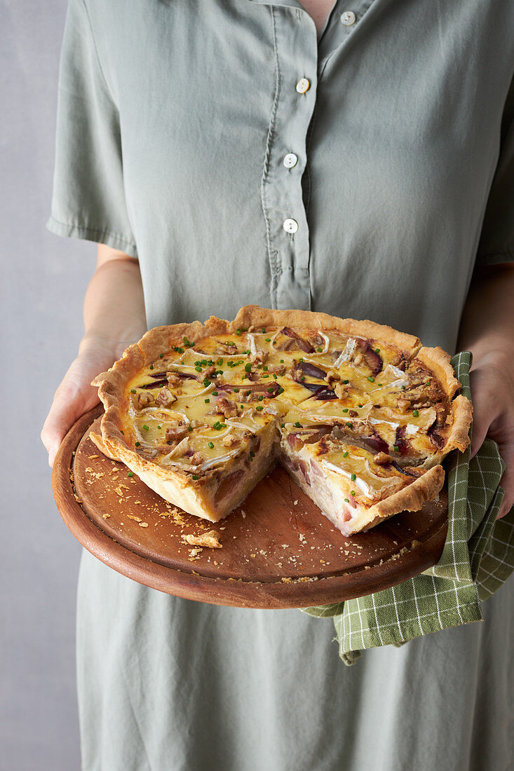 Woman holding cheese tart with walnuts