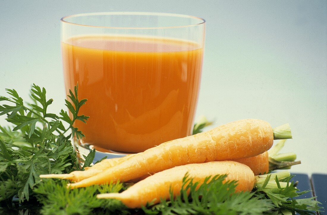 Ein Glas Möhrensaft, Deko: frische Möhren mit Grün