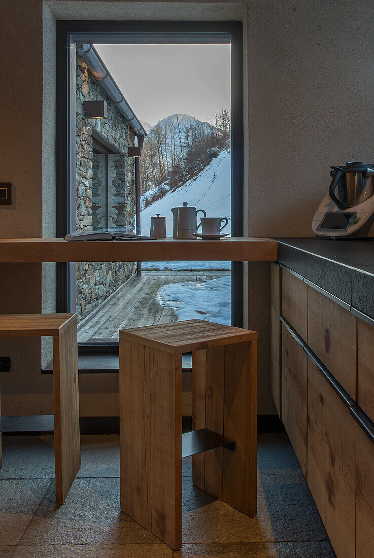 Solid-wood breakfast bar and bar stools in front of picture window