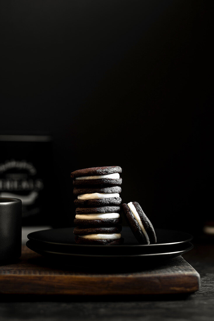 Oreo-Kekse gestapelt auf schwarzem Teller vor schwarzem Hintergrund