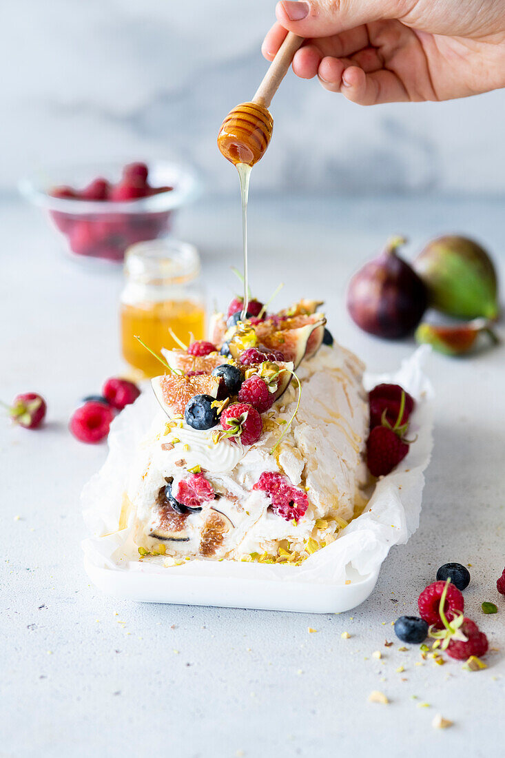 Meringue roll with figs and berries drizzled with honey