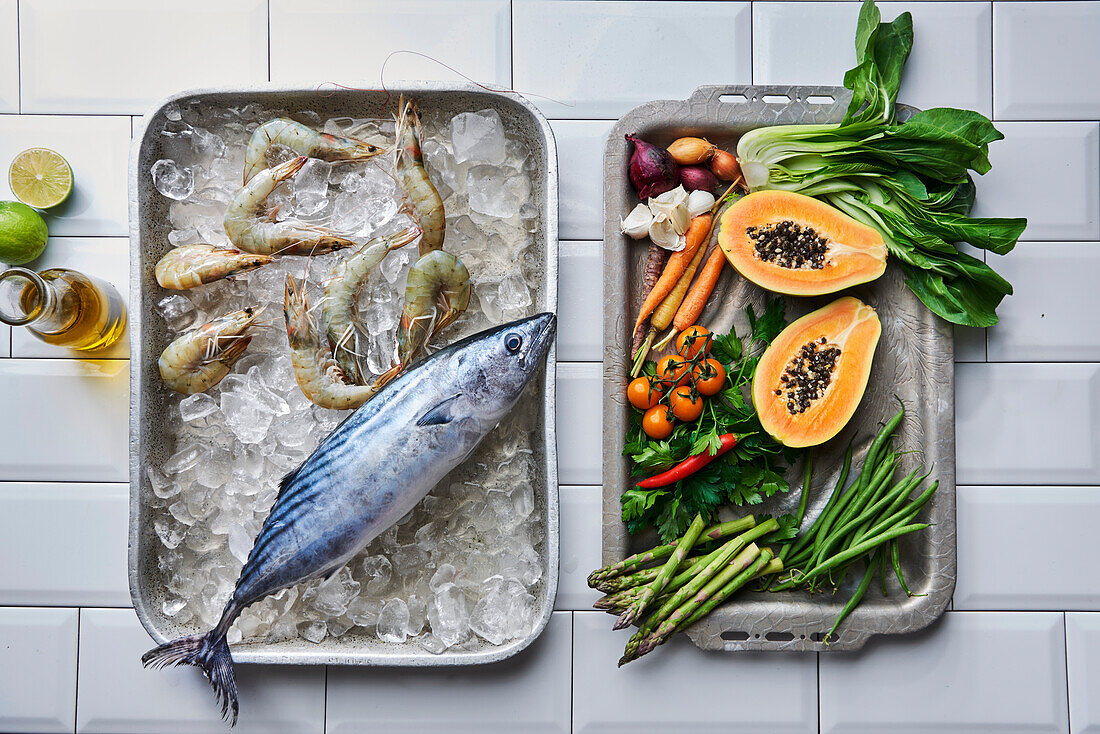 Bonito and tiger prawns on ice, with vegetables and papaya on oven trays