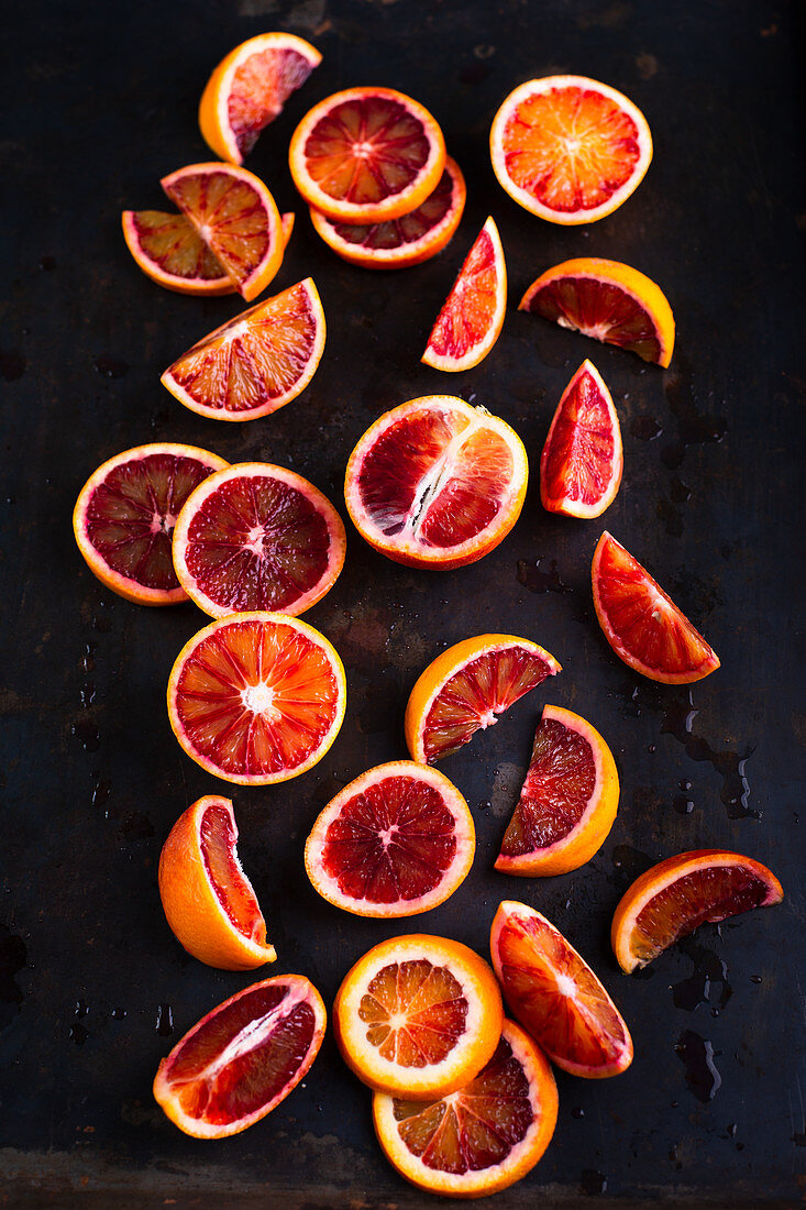 Blood oranges in slices and wedges on a black background