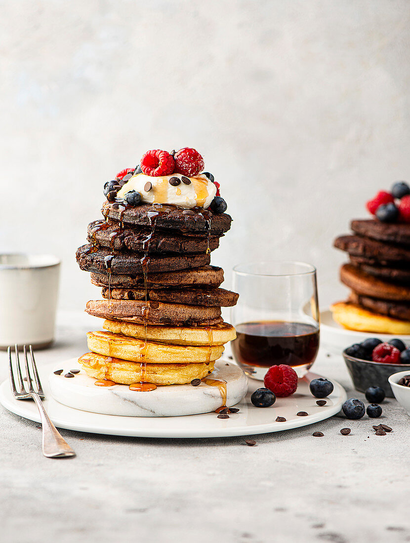 Different pancakes stacked with maple syrup and berries