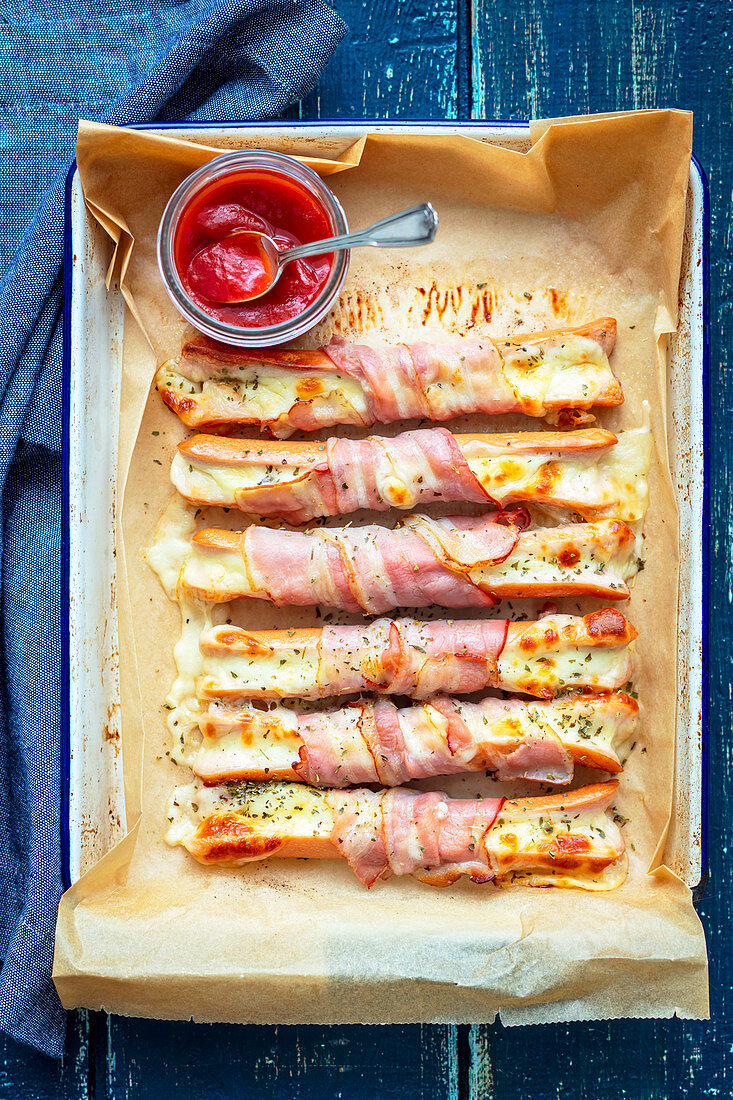 Baked sausages with cheese, wrapped with bacon