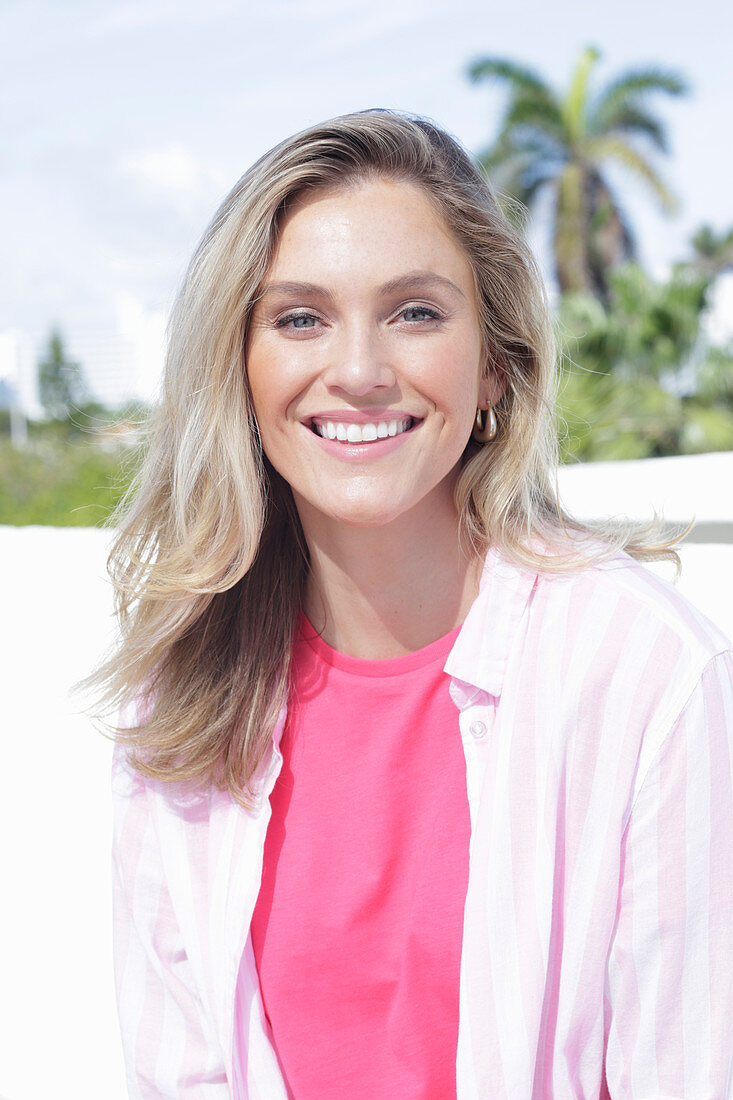 A young blonde woman wearing a pink top and a striped shirt