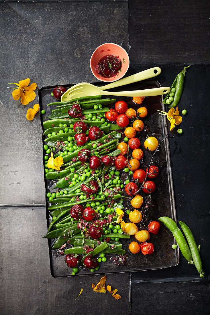 Sweet and sour pea salad with sweet cherries and caramelized tomatoes