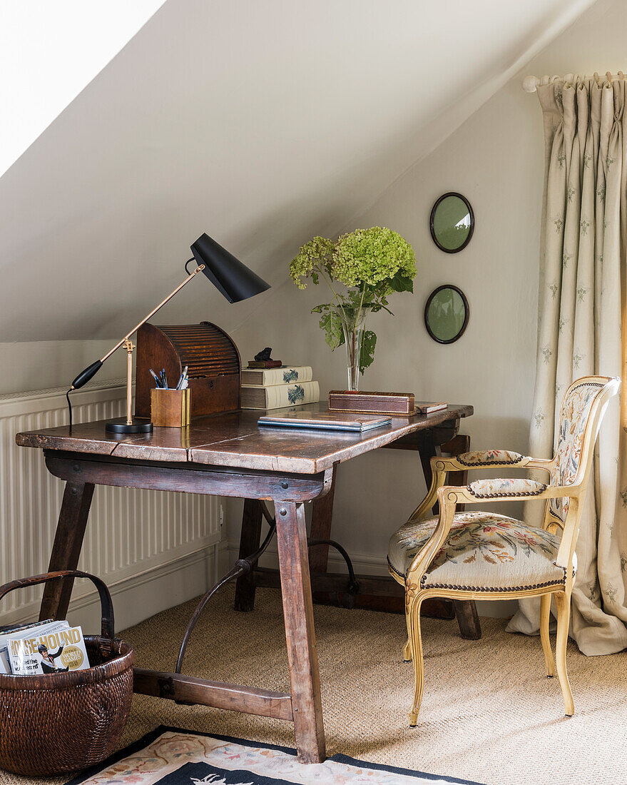 Tapestry chair at dar wooden desk with lamp and flowers