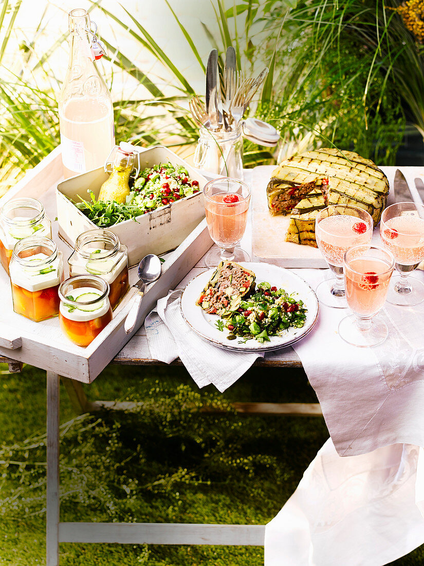 Gedeckter Tisch im sommerlichen Garten mit Hackbraten und Getränken