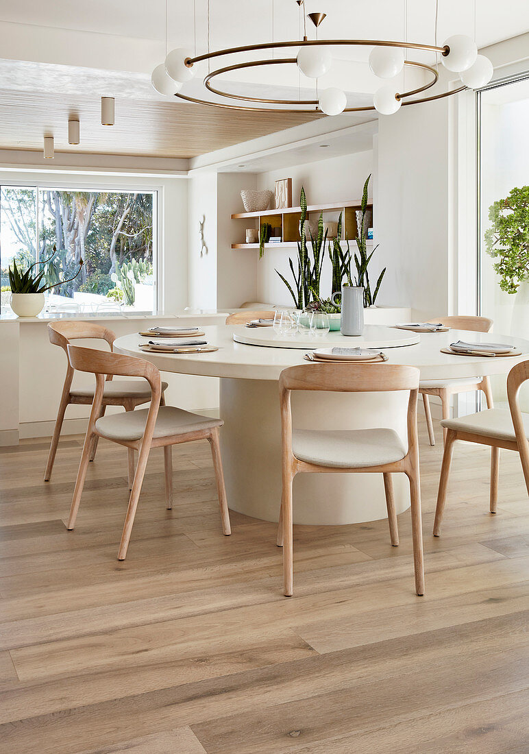 Großer runder Tisch mit hellen Holzstühlen im modernen Esszimmer