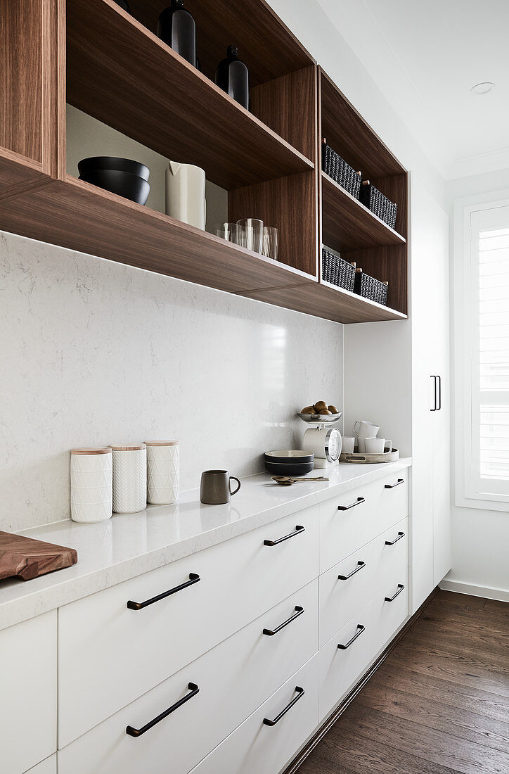 Narrow kitchen counter with white base units below open-fronted shelves