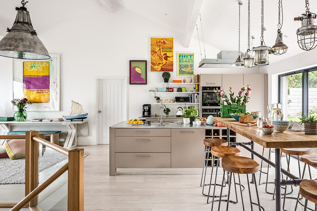 Reclaimed lights above breakfast bar with 1960s style artwork in open plan kitchen renovation