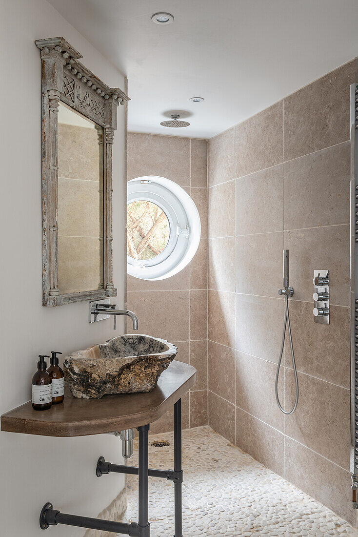 Neutral wet room with porthole window and Indonesian stone basin