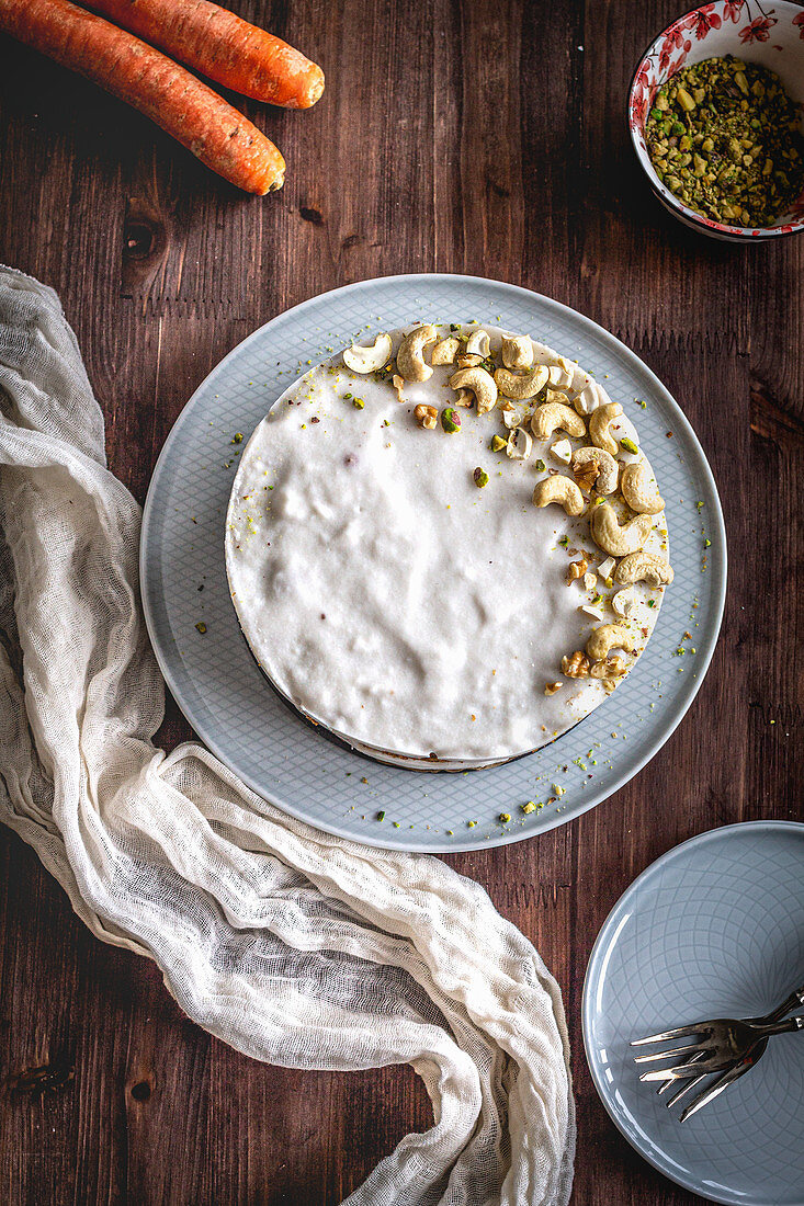 Carrot cake with icing and pistachio-cashew decorations