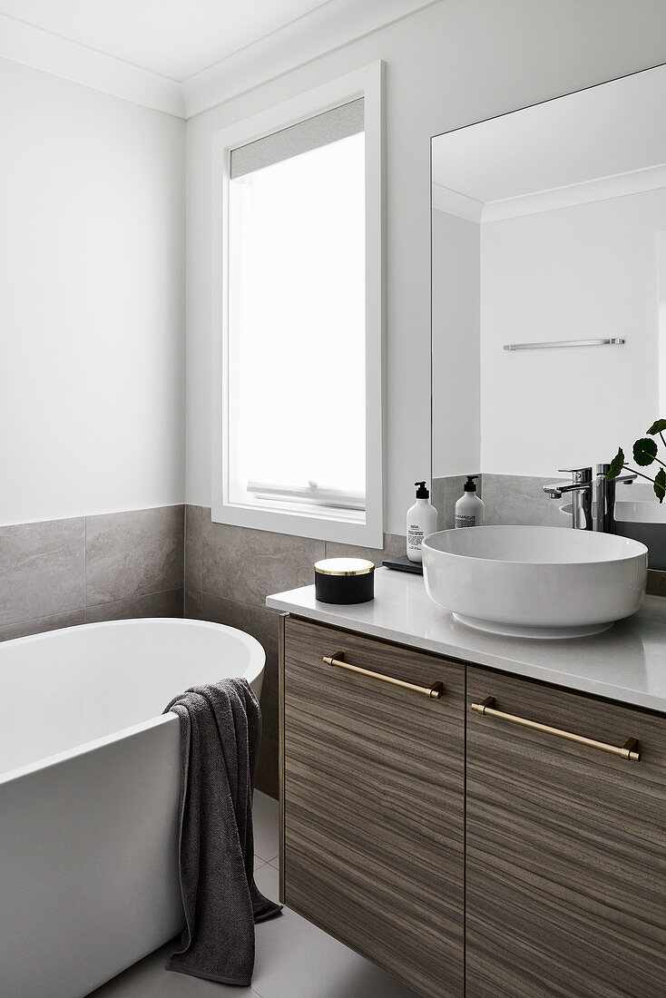 Free-standing bathtub in modern bathroom decorated in white and grey