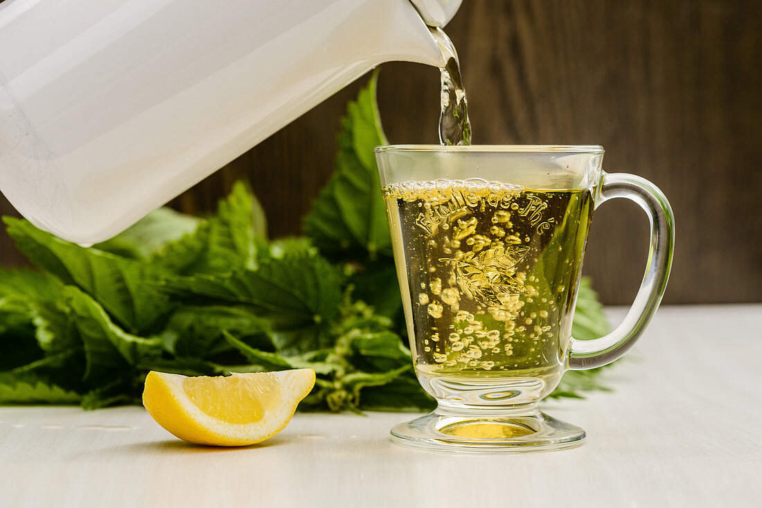 Nettle tea with lemon is poured into a glass cup