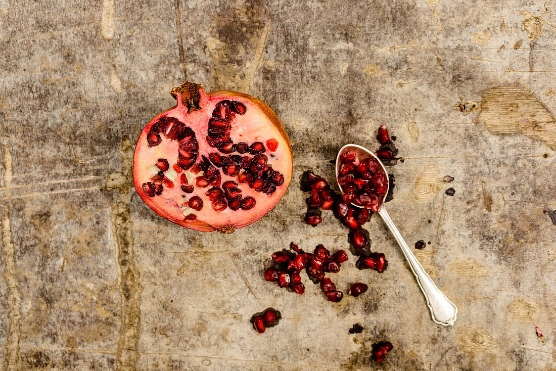 Half a pomegranate with seeds on a spoon
