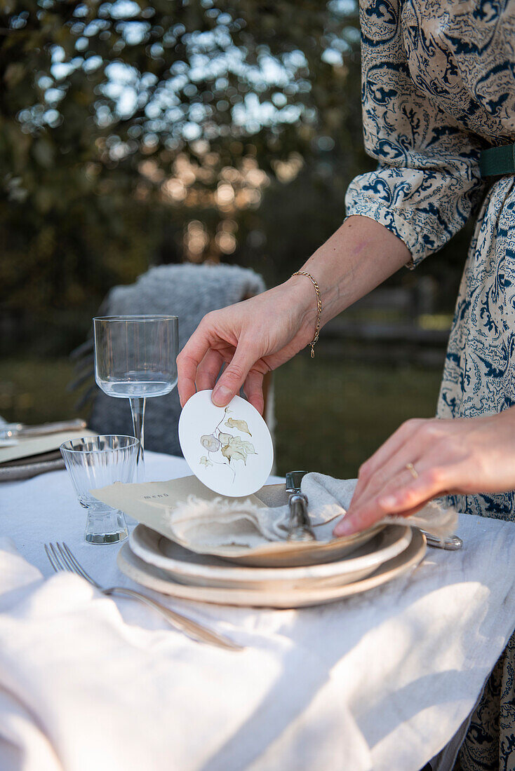 Place setting with linen napkin and decorated pendant on garden table