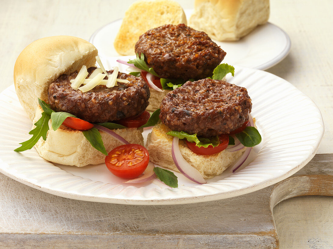 Mini burgers with a tomatoes and rocket on a plate