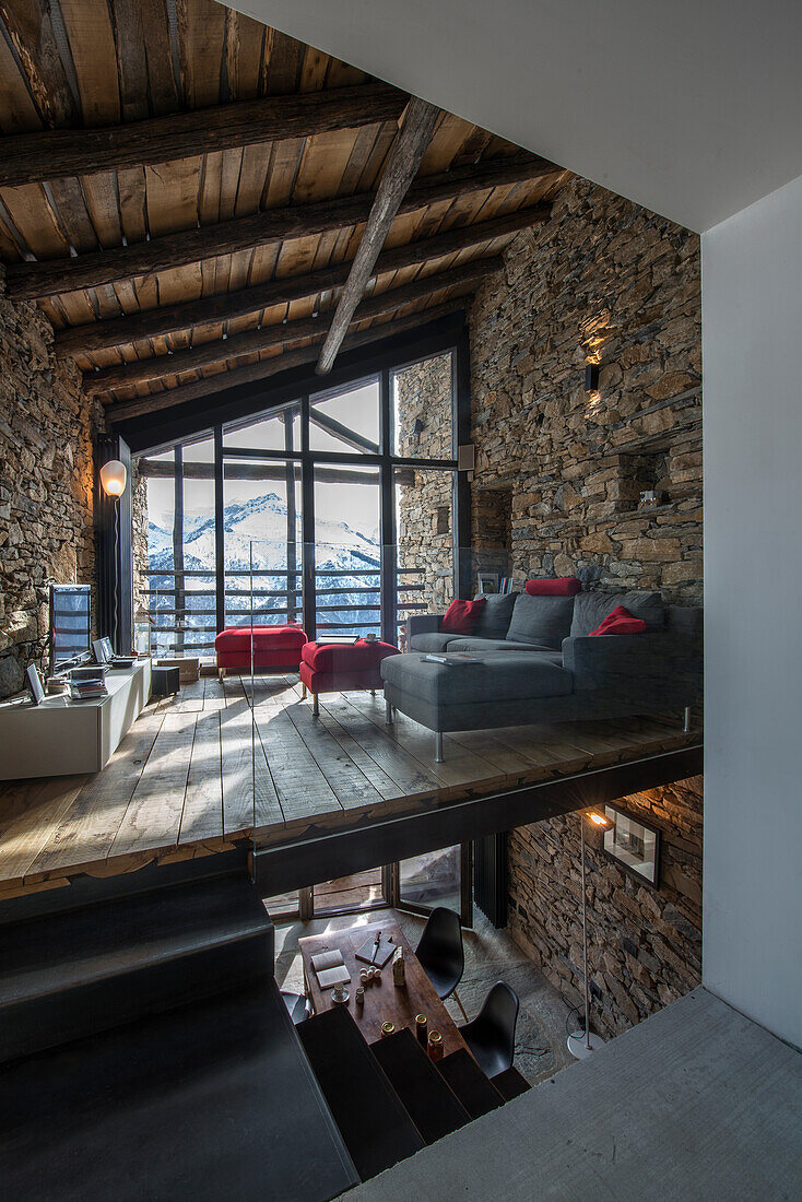 Moderne Lounge in offenem Wohnraum mit Natursteinwänden und Holzbalkendecke