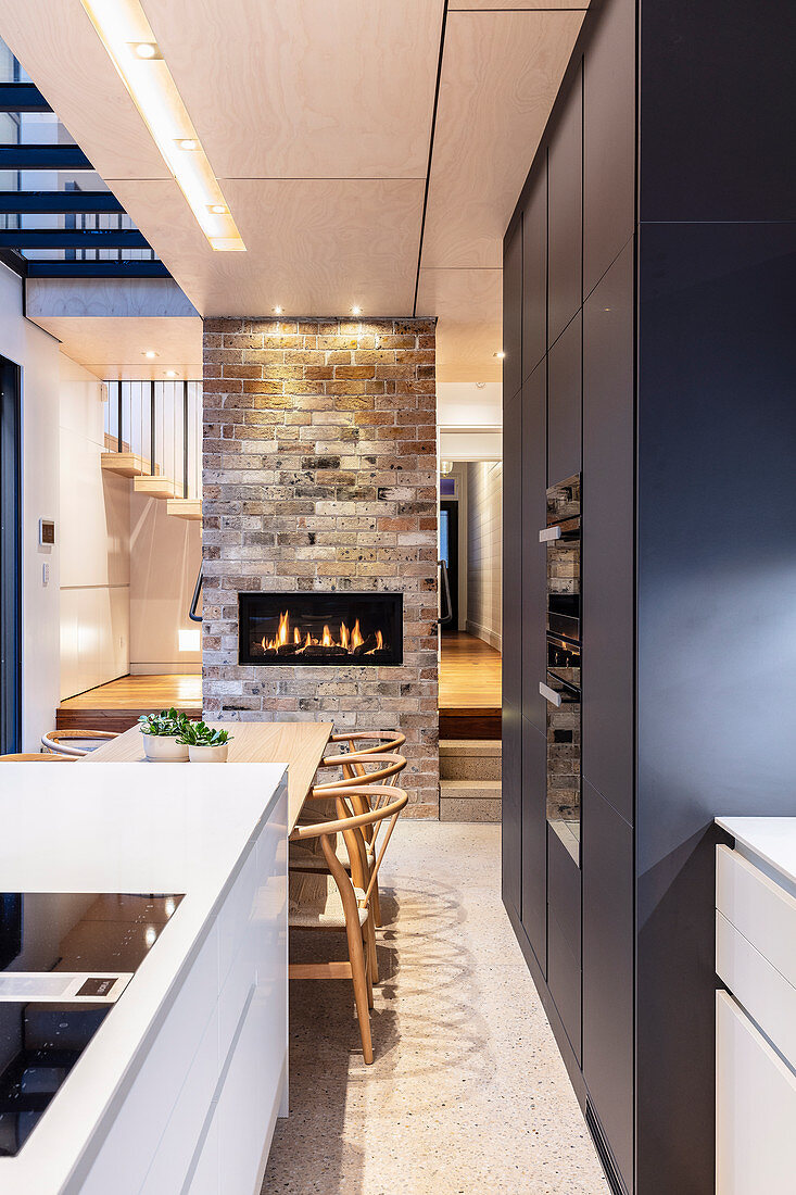 Moderne Wohnküche mit Kücheninsel, Esstisch und Kamin