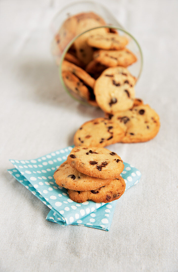 Chocolate chip cookies falling out of a jar