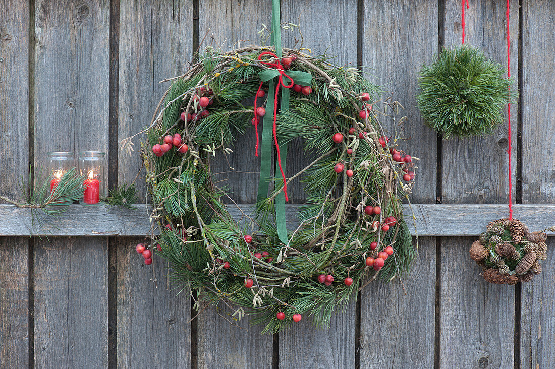 Wreath made of pine branches, ornamental apple and hazelnut, homemade ornaments made of pine needles, moss, and cones