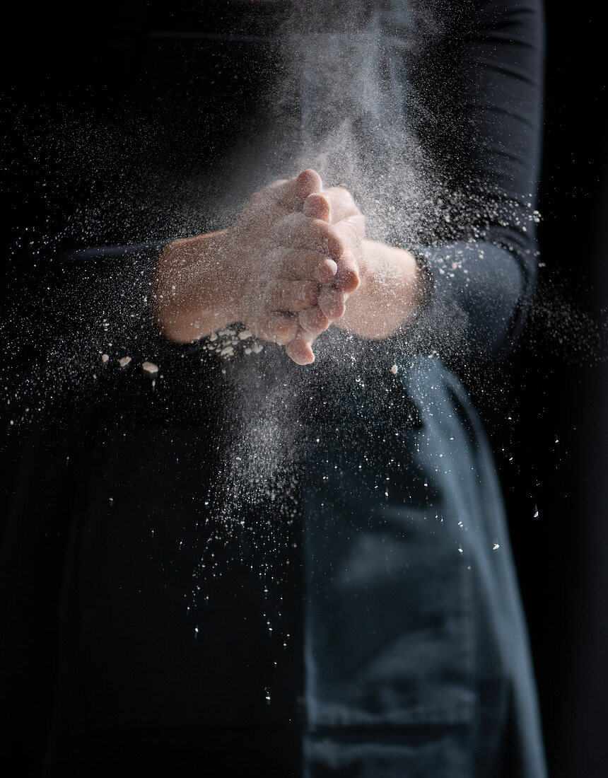 A woman knocking flour off her hands