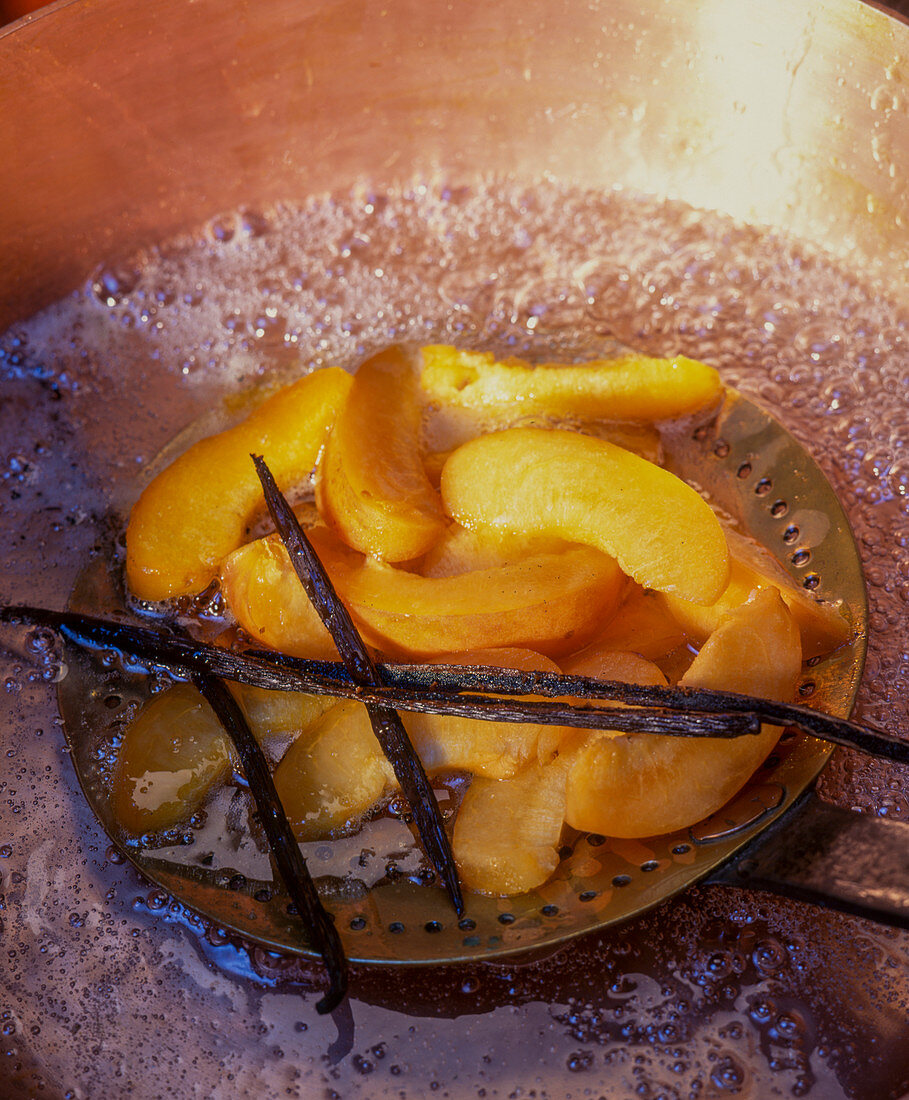 Preserves being made: apricot slices being removed from vanilla broth
