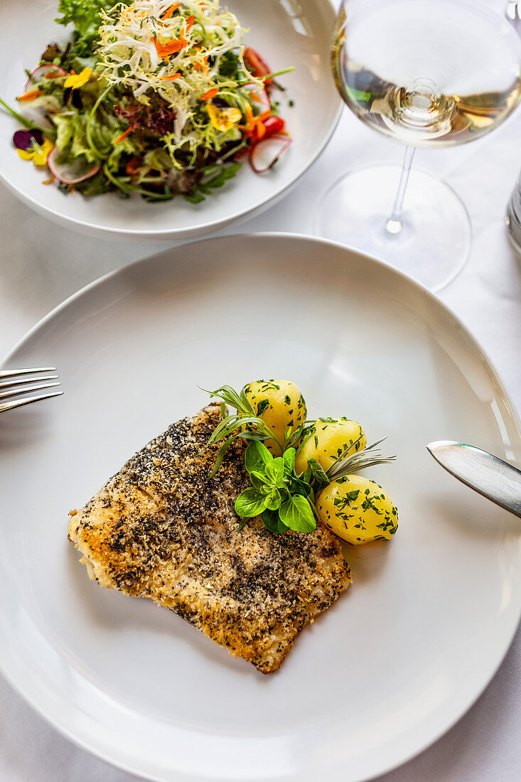 Fried fish in a poppy seed crust with potatoes and mixed salad