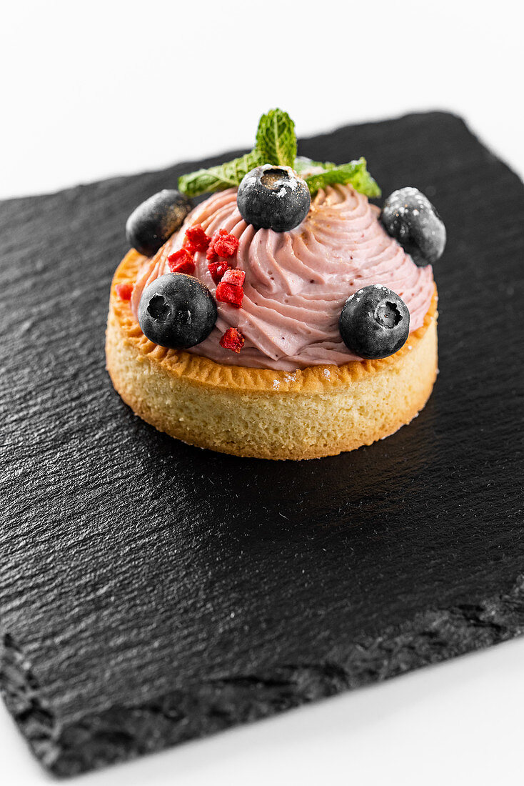 Törtchen mit Buttercreme und Heidelbeeren auf Schieferplatte