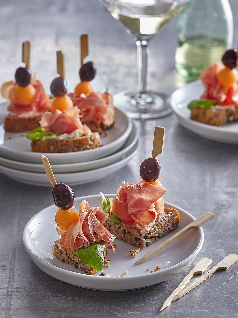 Canapés with prosciutto, melon and olives