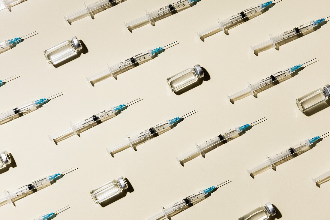 COVID-19 vaccine syringes and vials on pale background