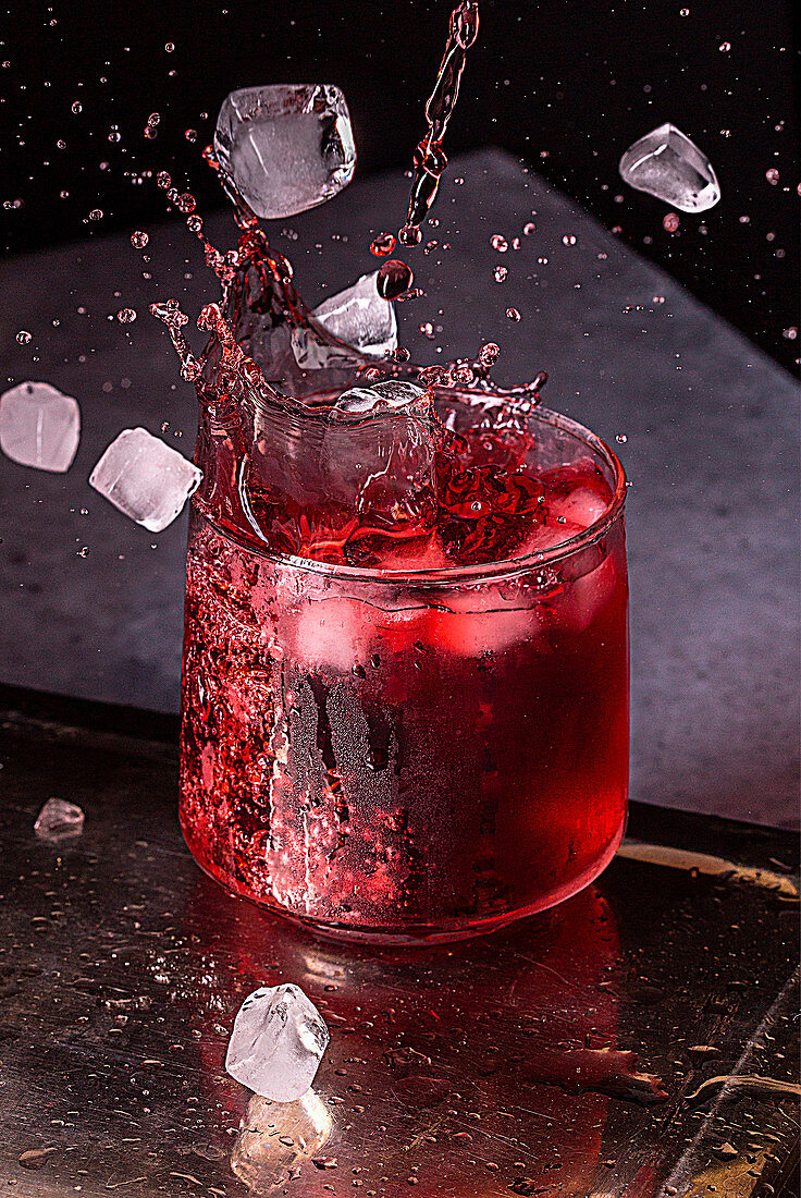 Splashing red wine with ice cubes in a glass